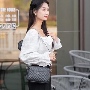 Detail of black chevron quilted crossbody bag with matching round coin purse attachment