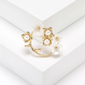 Golden flower vine brooch with white pearls and floral accents on a clean background