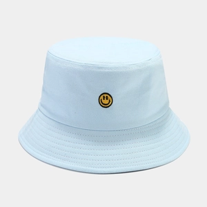 Detailed embroidery of a yellow smiley face on a light blue cotton canvas bucket hat