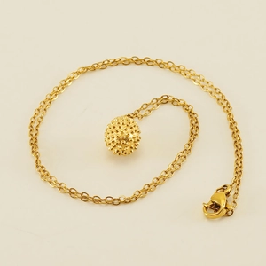 Gros plan du pendentif boule dorée à pointes avec collier à chaîne en spirale