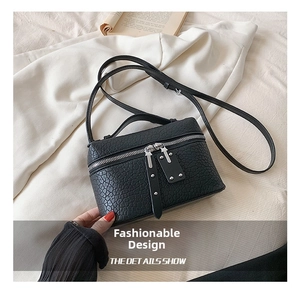 Close-up of black litchi pattern leather crossbody bag with dual zipper detail