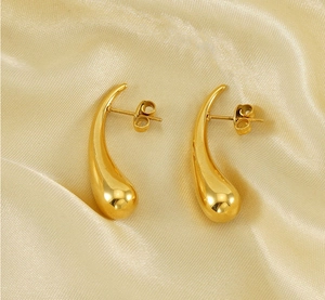 Detail of gold teardrop earrings on champagne satin with mirror polished finish