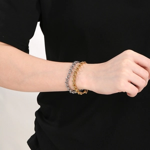 Détail de bracelets à maillons en acier inoxydable or 18k et argent au poignet avec fermoir