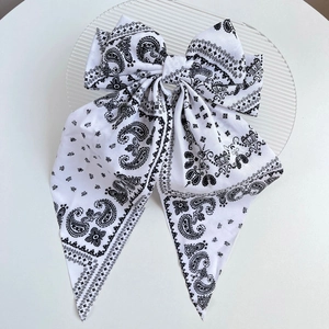 Detailed top view of large white paisley print bow hair clip on a clear glass plate