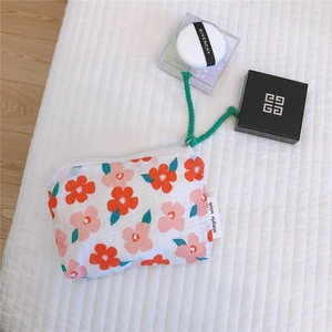 Close-up of floral fabric pouch with green drawstring pull and zipper closure detail