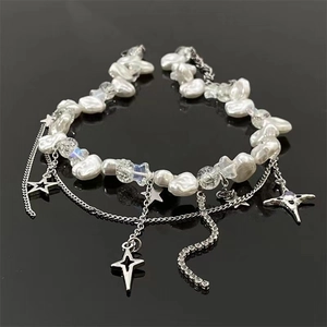Collana di perle barocche con ciondoli a stella e catena a nappe su sfondo nero