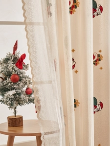 Close-up of semi-sheer lace Christmas curtain with Santa Claus embroidery and scalloped edges