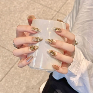 Champagnerfarbene Cat-Eye Kunstnägel mit Glitzer und Strasssteinen auf einer Hand