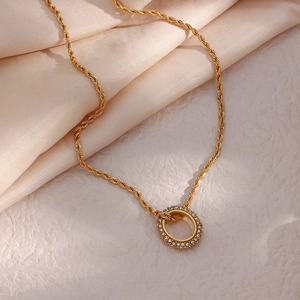 Detail of a gold rope chain necklace featuring a crystal-encrusted ring pendant on silk