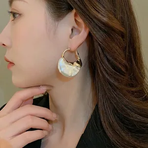 Baroque style gold irregular earrings with faux pearl texture shown on model