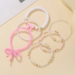 Detail view of pink beaded bracelets set with clay beads, pearls and bow charms