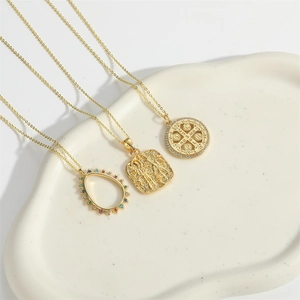 Detailed view of three vintage gold necklaces with religious pendants on a ceramic tray