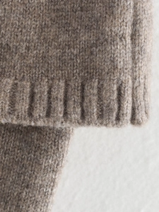 Macro view of taupe knit sweater detail showing thick plush texture and ribbed cuff finish