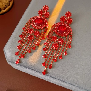 Dettaglio degli orecchini vintage a nappa rossi con strass su velluto grigio