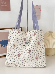 Off-white floral tote bag with purple bear print and textured fabric on metal stand