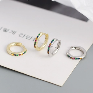 Close-up of gold and silver S925 huggie hoops featuring colorful rainbow cubic zirconia stones
