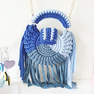 Detail of handmade crochet semicircular bag with multi-tone blue fringes and gold chain strap