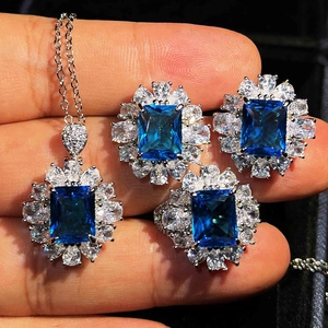 Detailed view of silver jewelry set with large blue gemstones and sparkling halo accents