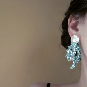 Détail d'une boucle d'oreille en argent avec franges en perles acryliques bleues