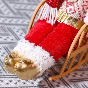 Detail of Christmas figure with gold boots and red velvet pants on a beige rocking chair