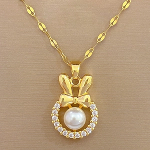 Detailed macro view of a gold bow necklace featuring a zircon ring and a lustrous white pearl