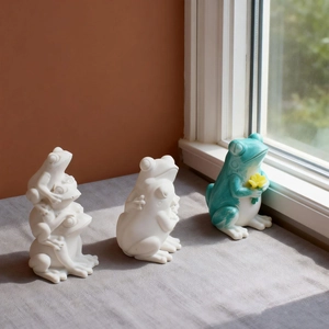 Trois figurines de grenouilles décoratives en résine avec finition mate sur pierre