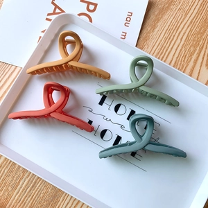 Détail de quatre grandes pinces à cheveux mates de différentes couleurs terre