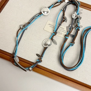 Macro detail of Bohemian suede necklace with braided blue cords and silver leaf charms