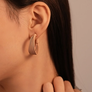 Detail view of pink multi-layer C-shaped earrings with brushed texture on model
