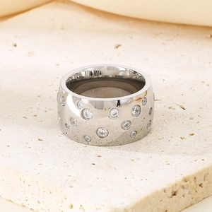 Macro shot of silver titanium steel ring with inlaid diamonds on a beige stone surface