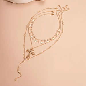 Detail of three-layer gold necklace featuring rhinestone cross and star pendants