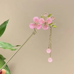 Detail einer goldenen Haarnadel mit rosa Blütenblättern und eleganten Quasten