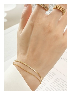 Close-up of double-layered gold snake chain bracelet and matching ring on model