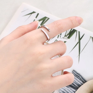 Anello regolabile in argento minimalista indossato all'indice con un bicchiere di vetro