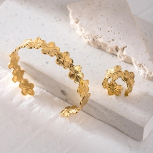 Dettaglio del set bracciale e anello a fiori dorati con trama a coste incise
