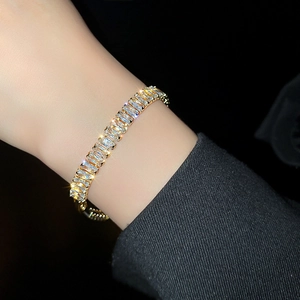 Detailed view of luxury gold tennis bracelet with rectangular zircons on model's wrist