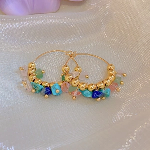 Detail view of gold hoop earrings with multi-colored natural stone beads on mesh fabric