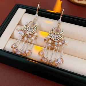 Detail of gold tassel earrings featuring pearls, crystals and amber beaded chains