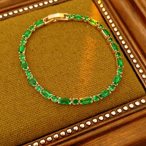 Detail shot of sparkling green emerald tennis bracelet on a vintage mustard fabric