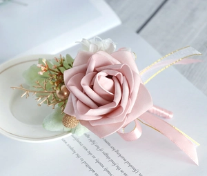 Macro view of dusty pink PE rose boutonniere with gold-edged ribbon on a ceramic plate