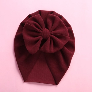 Macro view of burgundy baby headband featuring a large bow and soft knitted texture