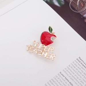 Broche pomme scintillante Super Teacher avec émail rouge et cristaux sur fond de magazine chic