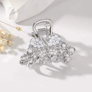 Detailed view of silver butterfly hair claw with white pearls on elegant setup