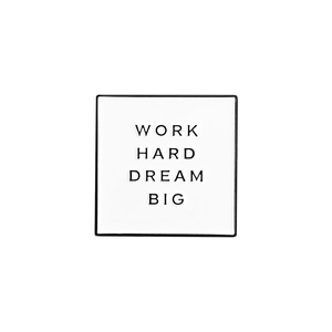 Close-up of enamel pin with Work Hard Dream Big text on a white square alloy badge