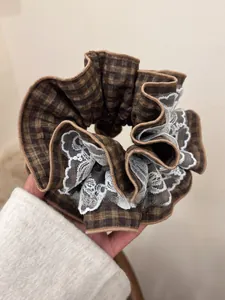 Detailed view of large retro red plaid scrunchie with delicate white floral lace trim