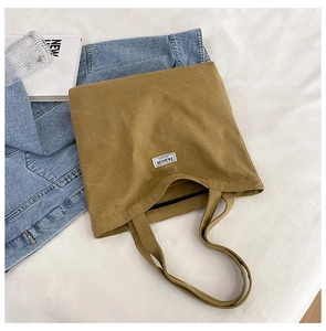 Detail view of khaki canvas tote bag with a white label on textured fabric background