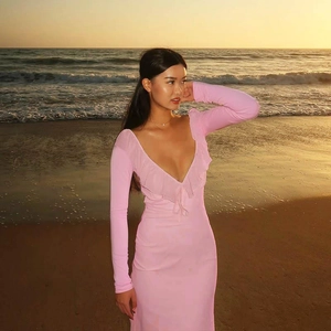Detail of pink slim fit dress with ruffle trim and deep V-neck at sunset beach