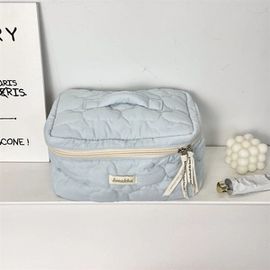 Detail of light blue quilted makeup bag with heart pattern and ribbon zipper pull