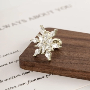Coffee gold snowflake cartilage stud with sparkling zircon crystals on vintage book background