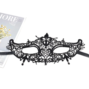 Detail view of intricate black lace mask with floral patterns and satin ribbon ties